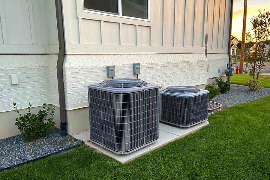 Two gray AC units on concrete pads