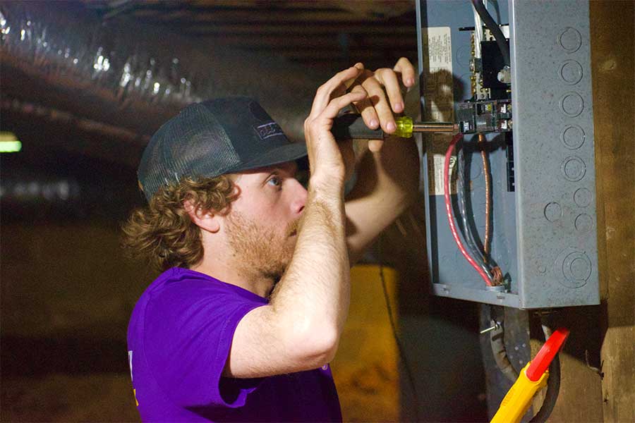 Technician repairing wiring and components inside a residential electrical panel in Raleigh, NC